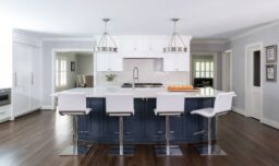 A modern kitchen featuring a blue painted island, complementing the ample white cabinetry, appliances and countertops.