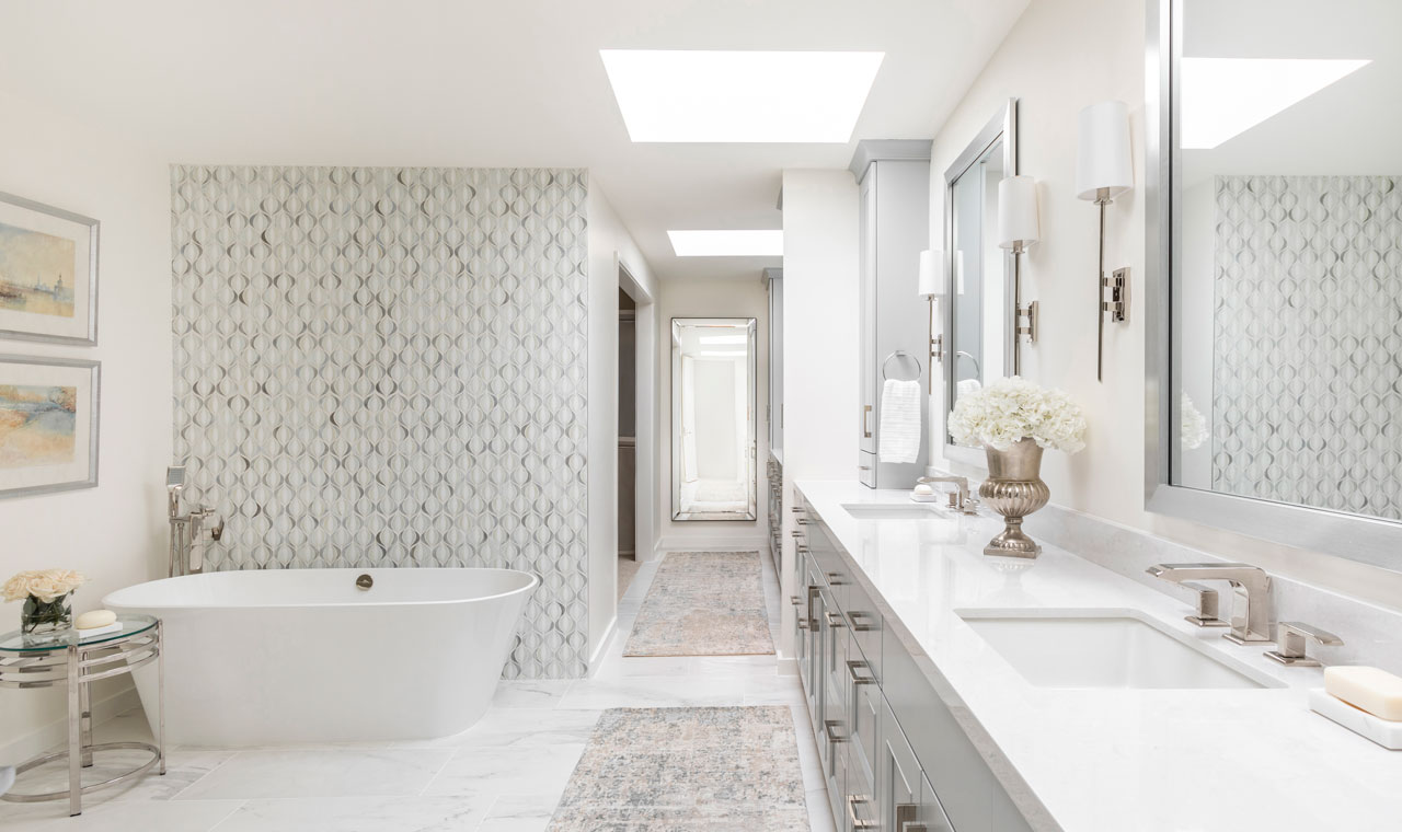 An elegant bathroom featuring a stunning standalone tub, a backdrop of a walk-in shower, dual sinks, and chic decor. The tranquil color palette of white, gray, and beige evokes a serene spa ambiance.