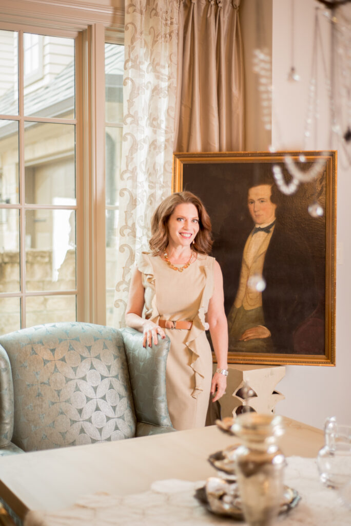 Pamela Hope stands in front of a family heirloom painting that she integrated into the design of her own dining room. She included a reupholstered chair and budgeted for window treatments.